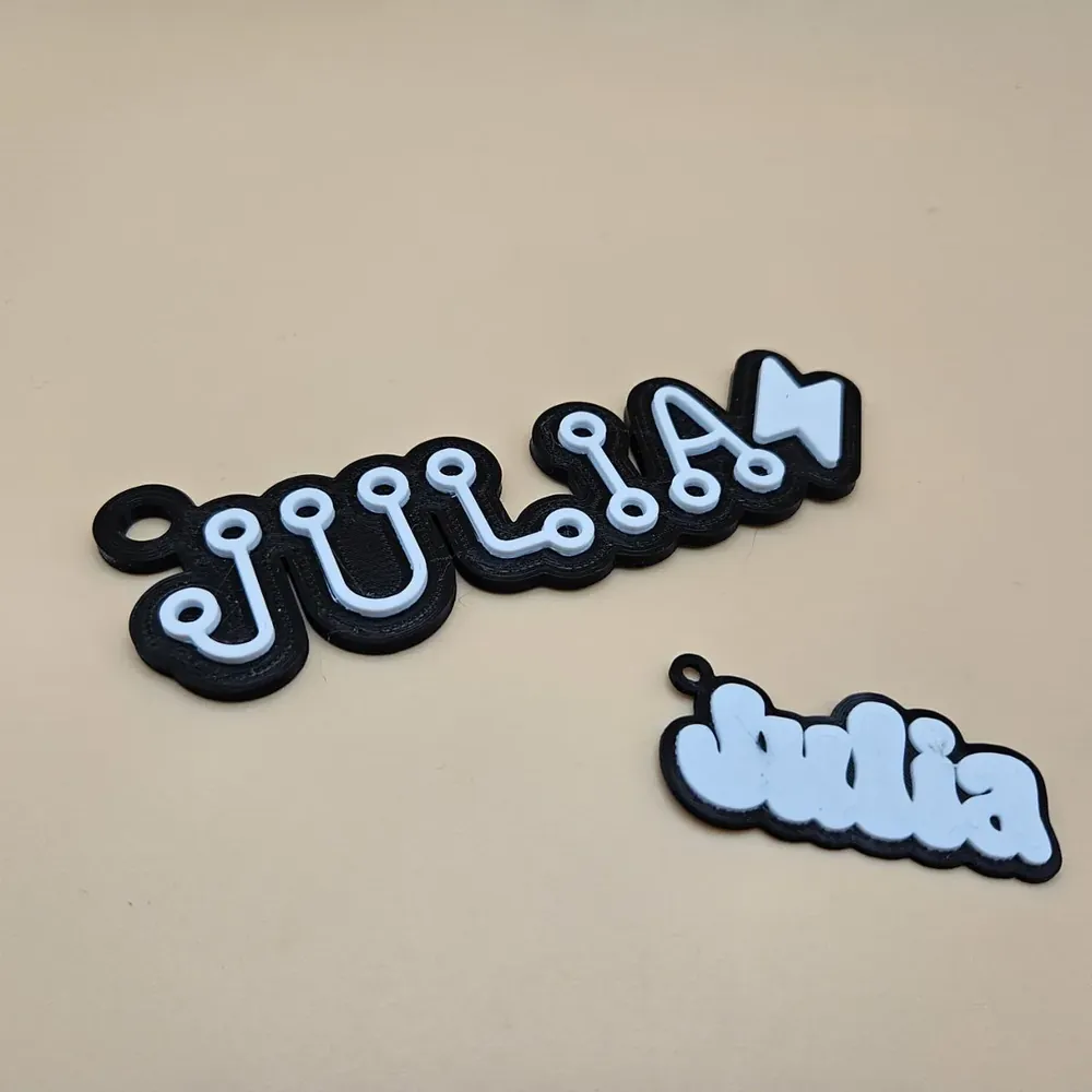 3D printed backpack tag with the name Julia in white on a black base