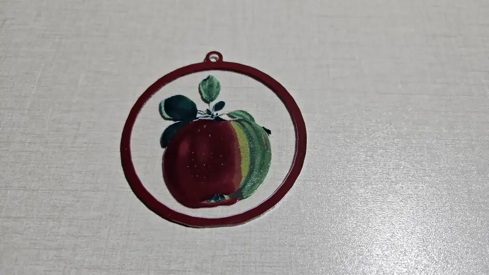 Adorno de acrílico transparente con una manzana roja impresa dentro de un aro rojo