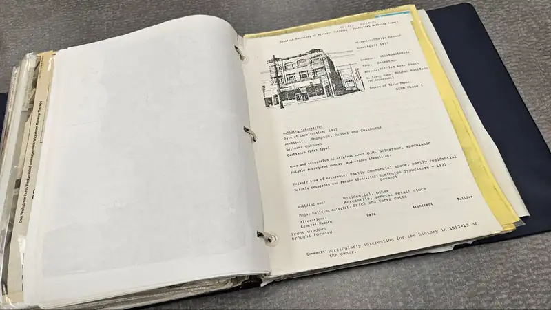Una carpeta abierta de informes históricos de edificios con un dibujo a pluma de una fachada de ladrillo