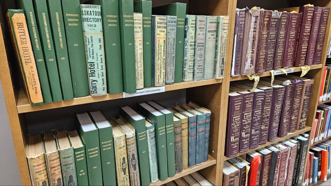 Estantes de biblioteca con directorios de la ciudad encuadernados en verde y granate desde principios del siglo XX