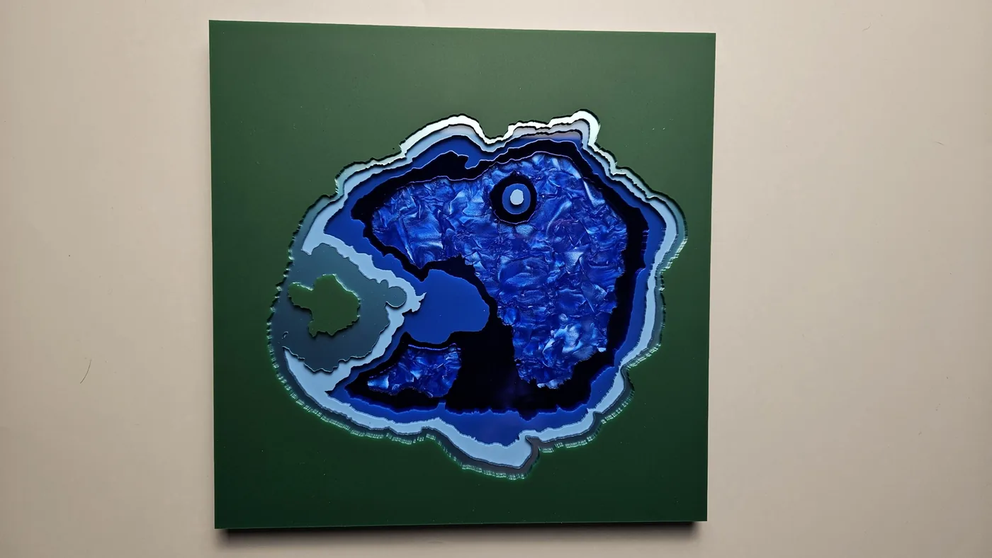 Un mapa de Crater Lake cortado a láser con franjas de profundidad azules por capas sobre un panel verde
