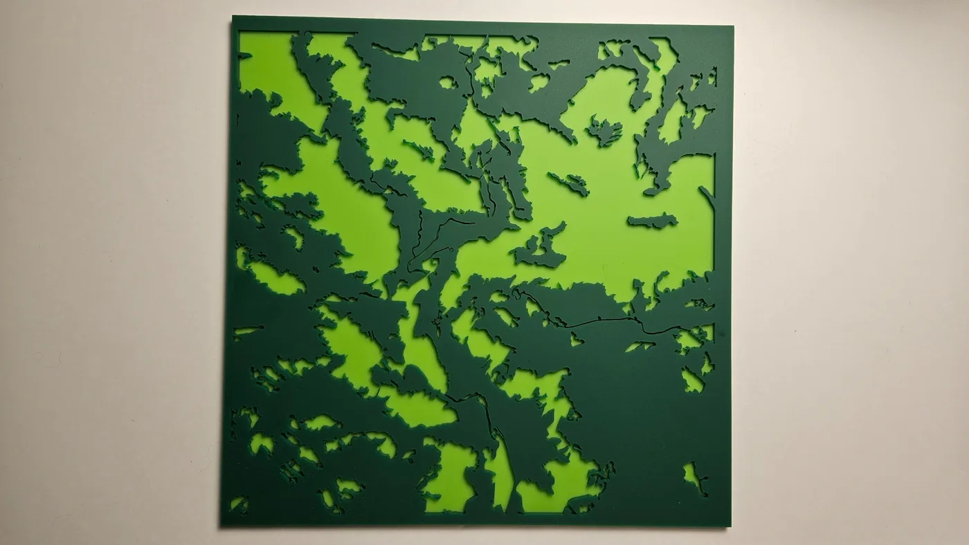 Un mapa cortado a láser en dos tonos de verde con la cubierta forestal y los claros