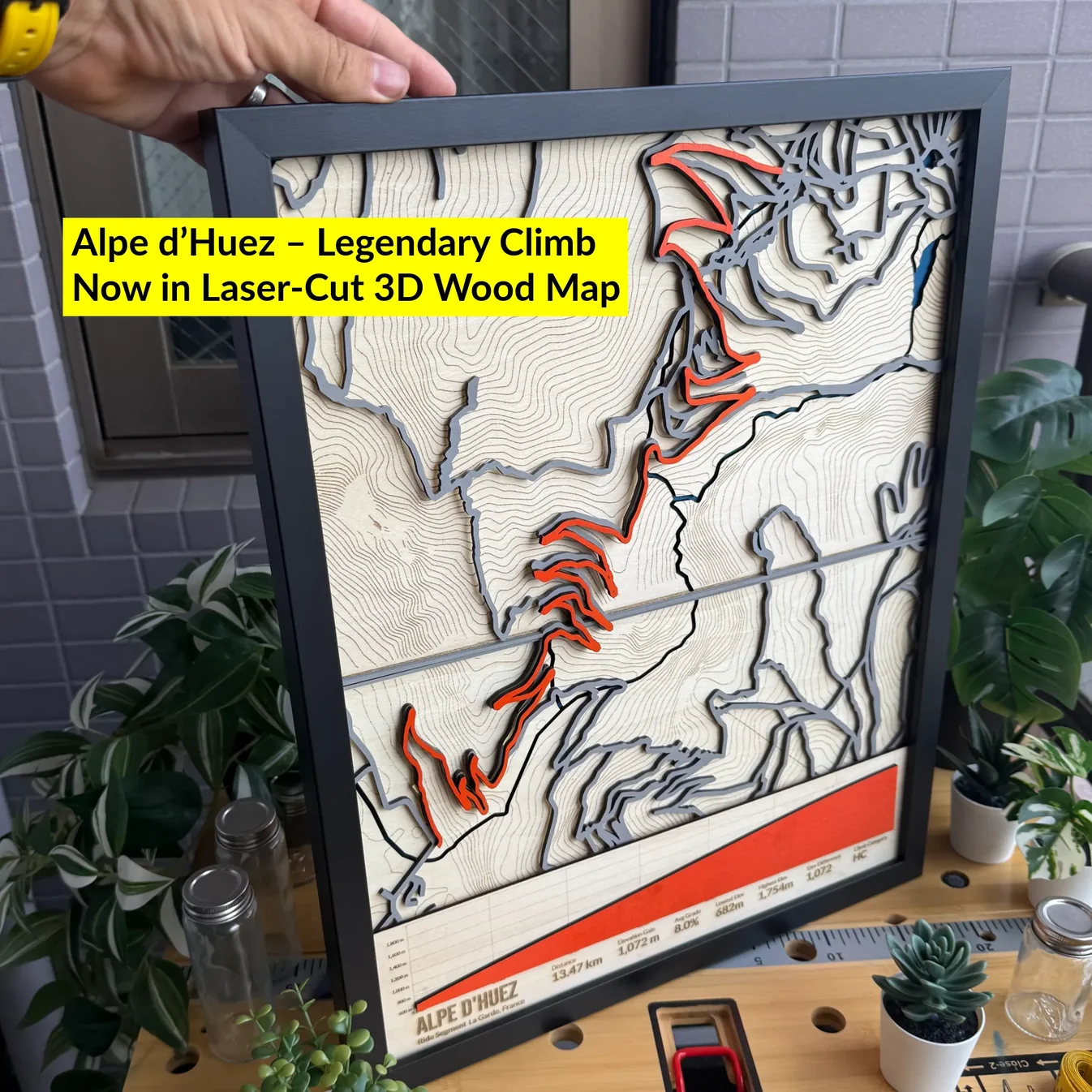 Laser-cut Alpe d'Huez cycling climb map with contour layers, the switchback route in orange, and an engraved elevation profile, made by The Magic Crayons with the MyLaserTools map generator.