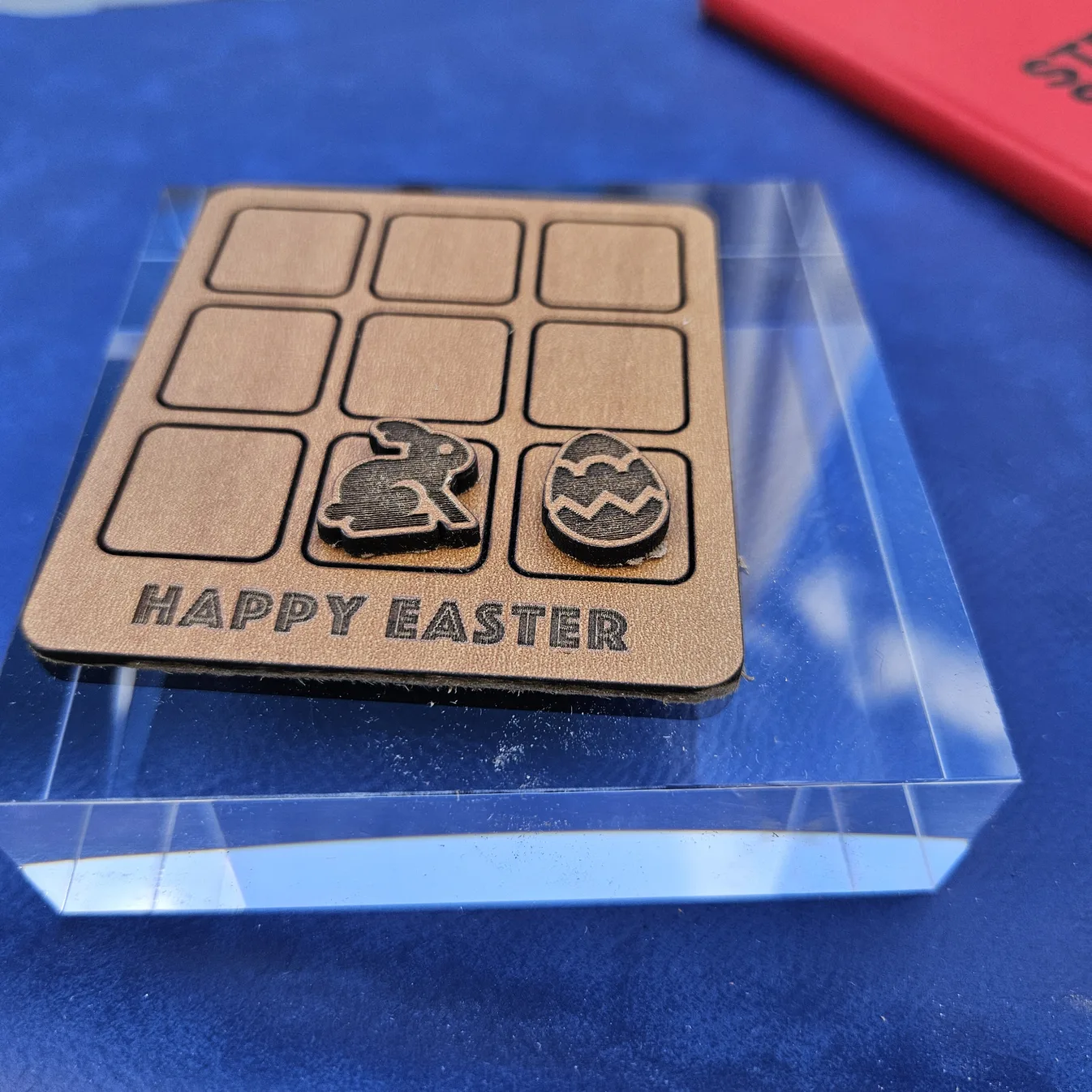 Laser-cut wooden Happy Easter tic-tac-toe board by Sofia Reyker, with bunny and decorated-egg game pieces and engraved lettering, made with MyLaserTools.